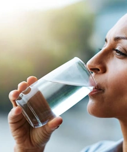 A woman is drinking a glass of water.