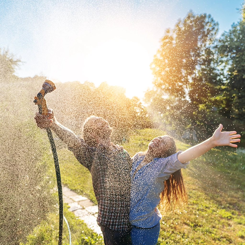 Couple enjoying pressurized water in garden.