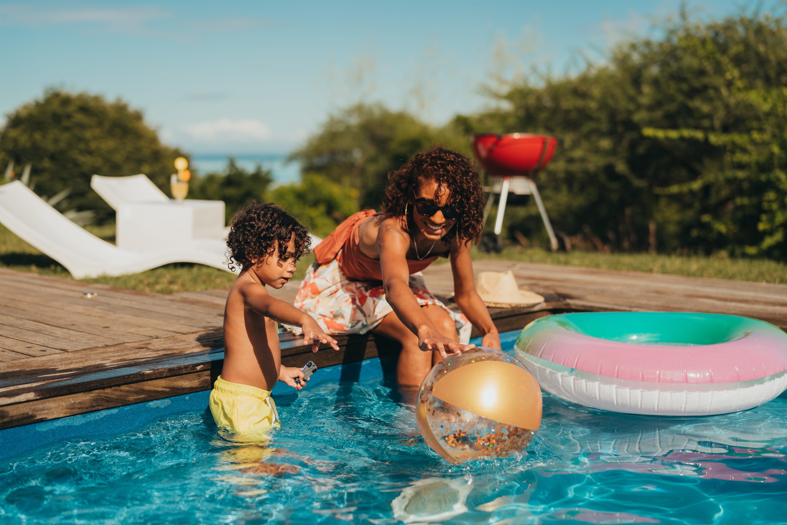Mother playing with toddler in pool.